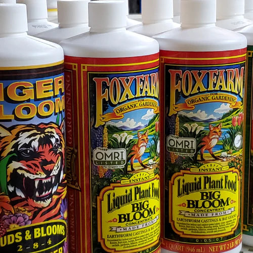 Bottles of FoxFarm liquid plant food, featuring vibrant labels with illustrations of a tiger and a fox in nature, promoting organic gardening.