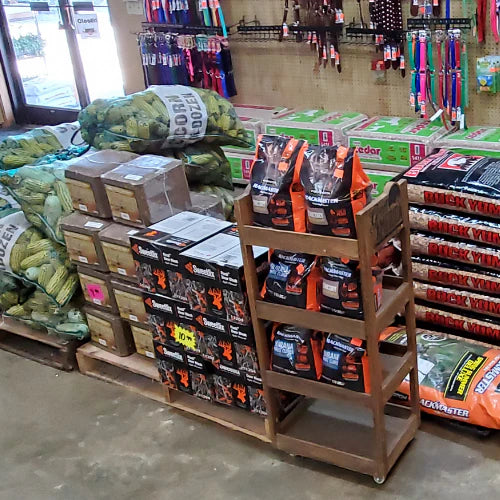 Store interior showing bags of seeds, stacked boxes, bags of soil, and garden supplies organized on shelves. Bright, organized, and inviting.